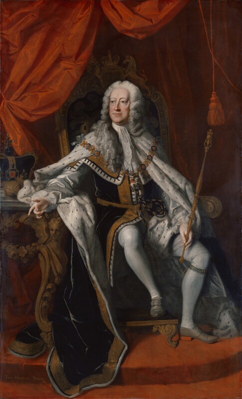 Portrait oil painting of King George II sat on a throne with a table to his right on which the crown sits. He is wearing white lace cravat and ruffles, blue ermine robes of state. white hose, and grey shoes. He has a long grey wig on. The backdrop is scarlet red drapes.