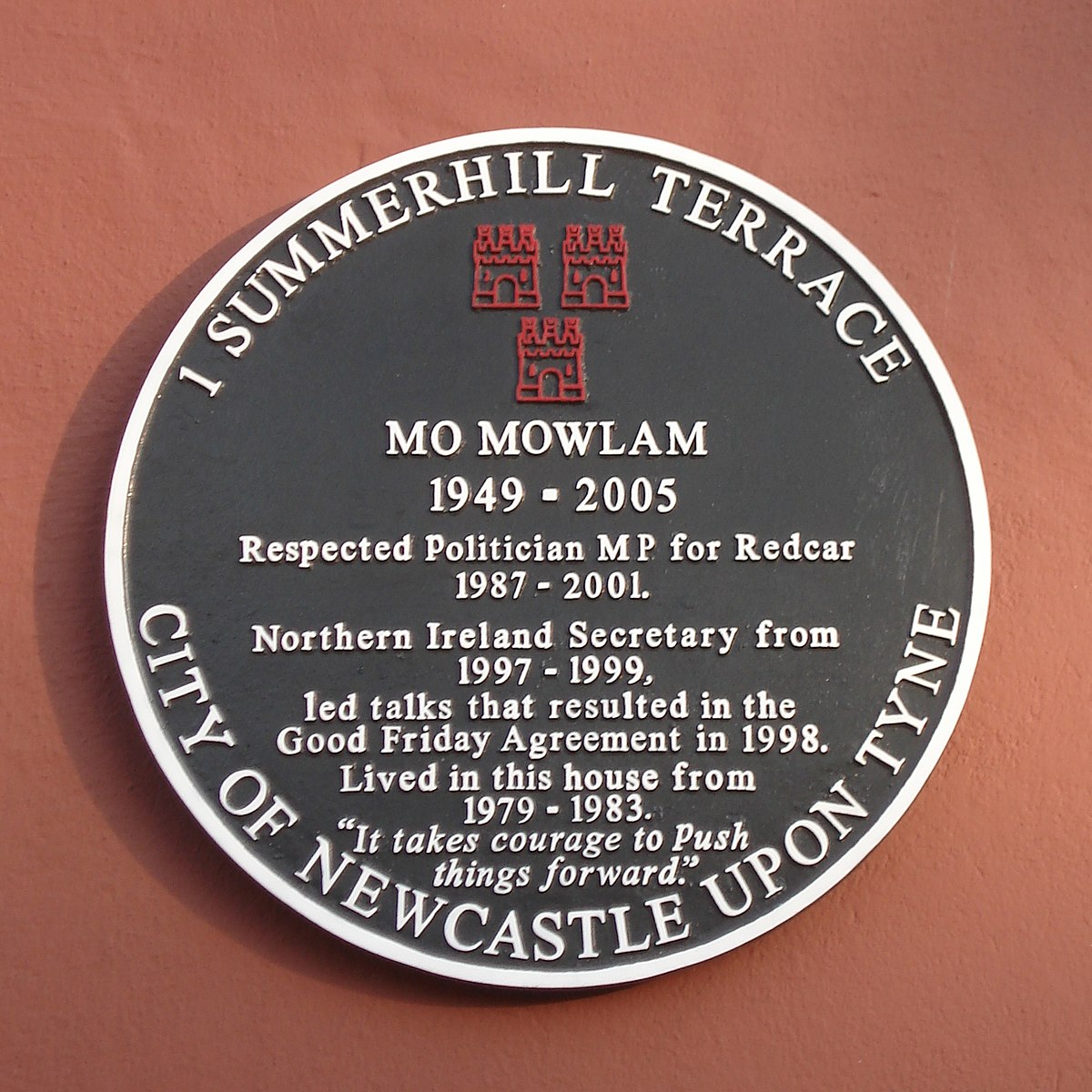 A plaque on a house. It reads: 1 Summerhill Terrace. Mo Mowlam, 1949-2005. Respected politician MP for Redcar 1987-2001. Northern Ireland Secretary from 1997-1999, led talks that resulted in the Good Friday Agreement in 1990. Lived in this house from 1979-1983. "It takes courage to push things forward." City of Newcastle Upon Tyne.
