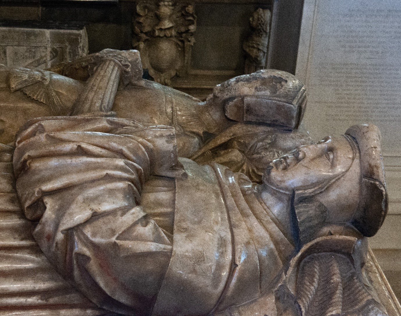 The top of a tomb with a man and woman lying side by side.