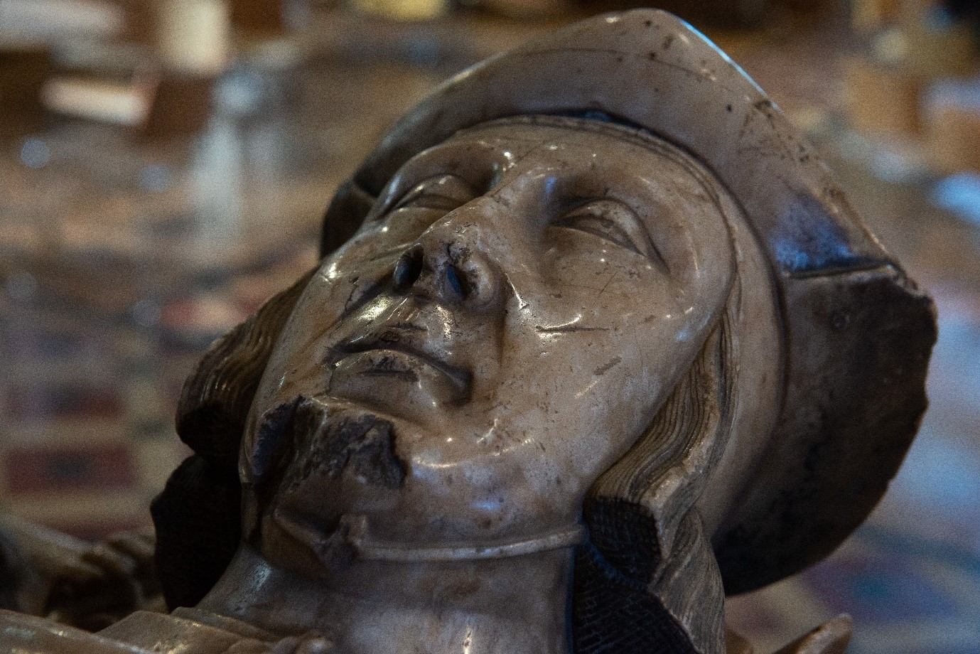 A close up photograph of part of the memorial. The man's head with coif and cap are in the image.