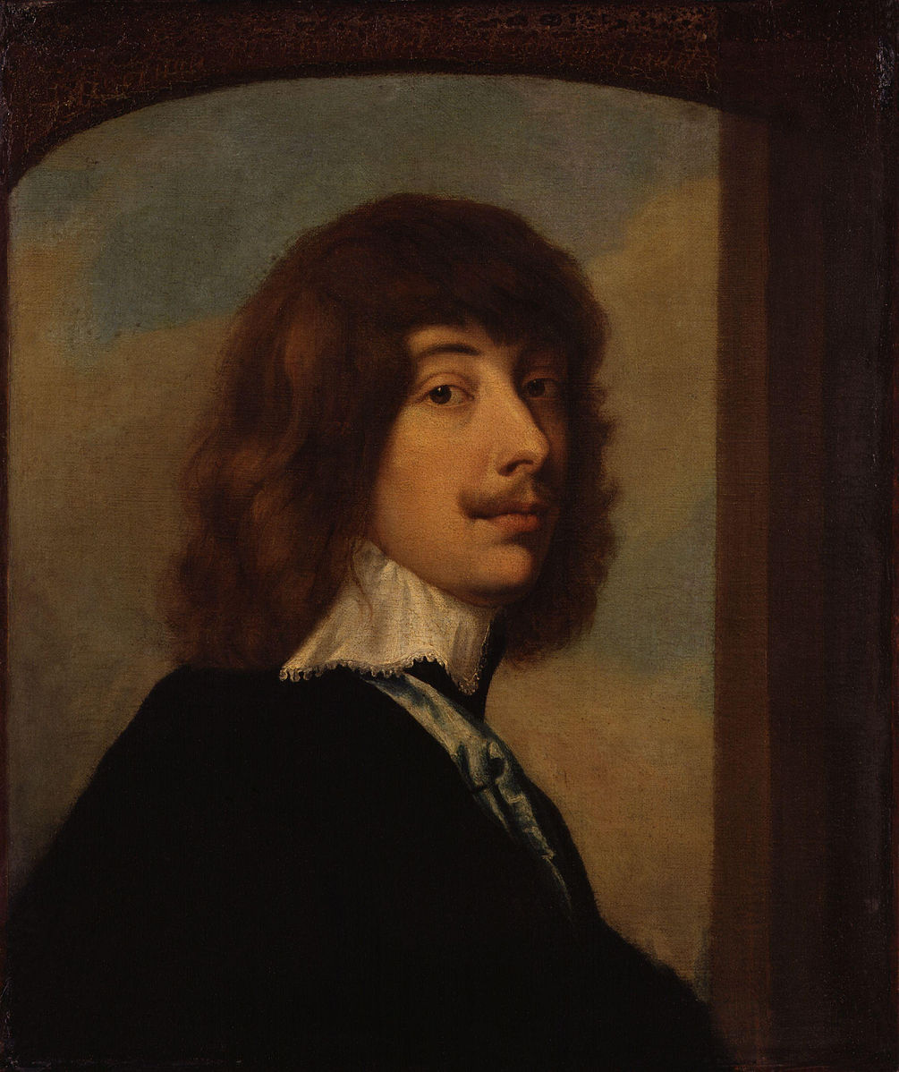 A white man with shoulder length dark hair and a moustache. He is sideways on and is looking out to the viewer.
