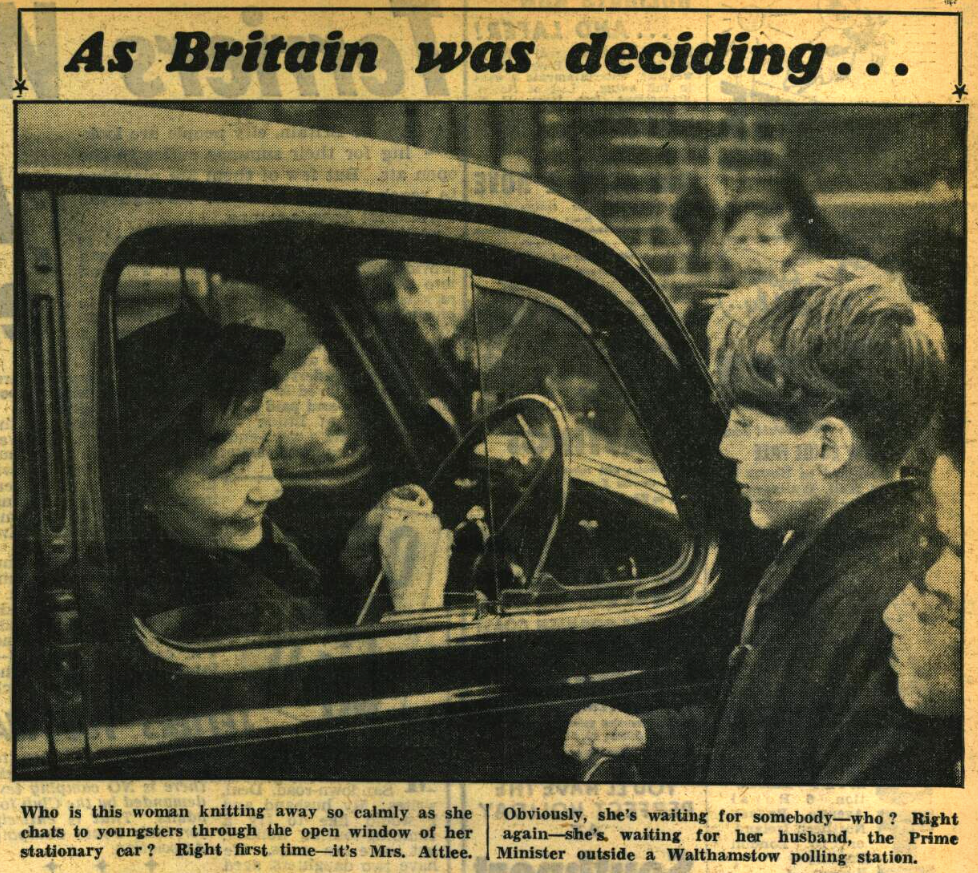 A clipping from a newspaper. There is a black and white photograph of a woman sat behind the wheel of a car knitting and talking to some children. Above the picture are the words 'As Britain was deciding...' Below the picture it says 'Who is this woman knitting away so calmly as she chats to youngsters through the open window of her stationary car? Right first time - it's Mrs. Attlee. Obviously, she's waiting for somebody - who? Right again - she's waiting for her husband, the Prime Minister outside a Walthamstow polling station.