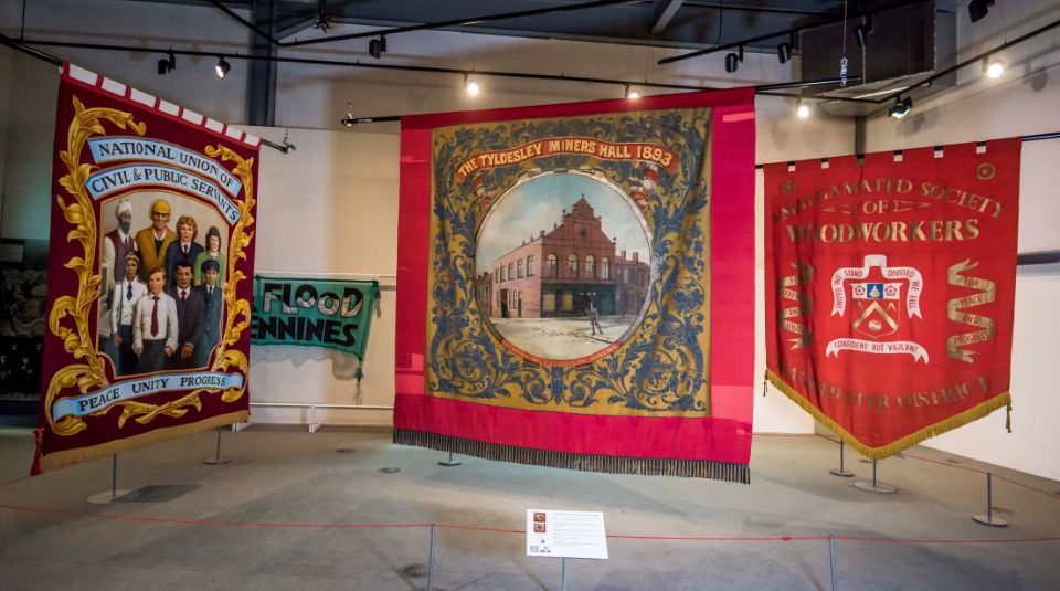 Three large protestors banners on display in a museum exhibition room