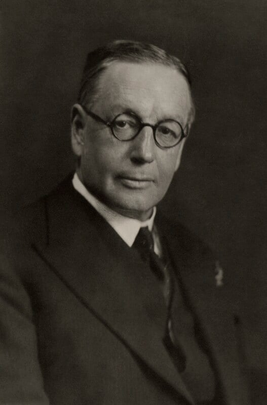 A man with glasses wearing a three piece suit