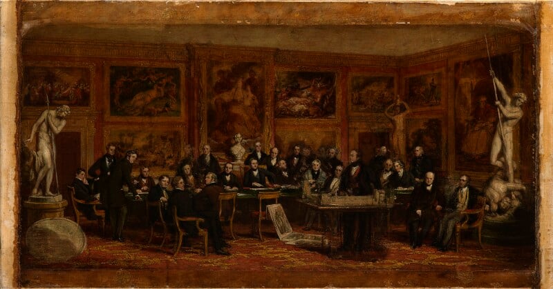 A group of men sitting in a room surrounded by artworks and two statues
