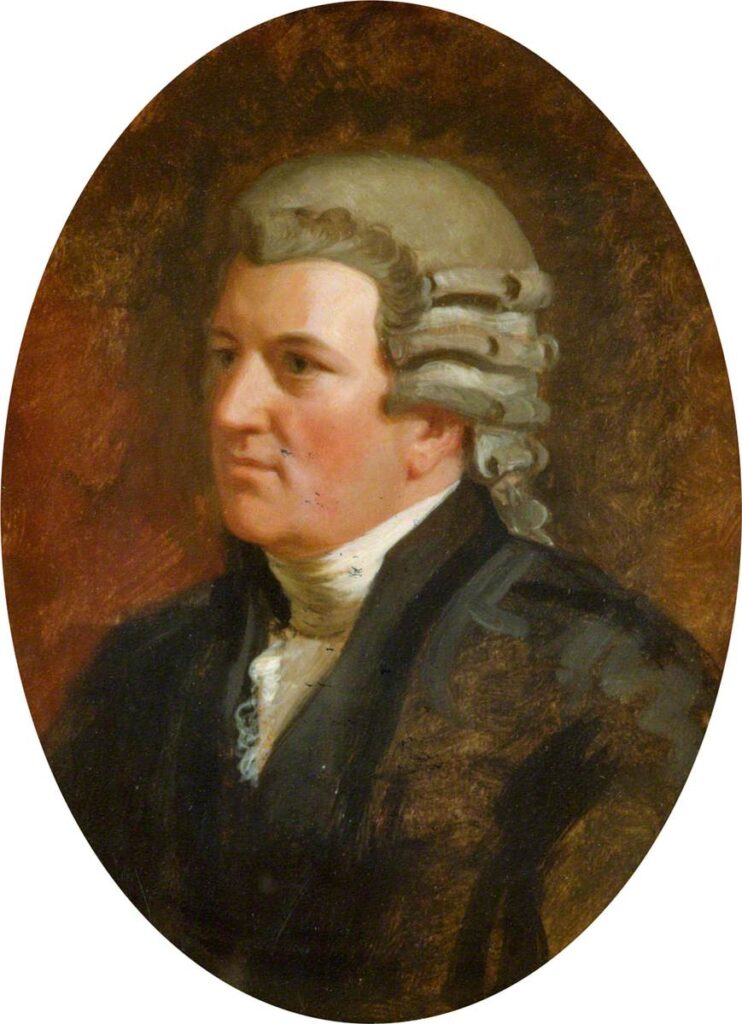 An oval half-length portrait of a man looking to his right. He is in a black coat and jacket with white frilled necktie. He is clean shaven with a grey curled wig.