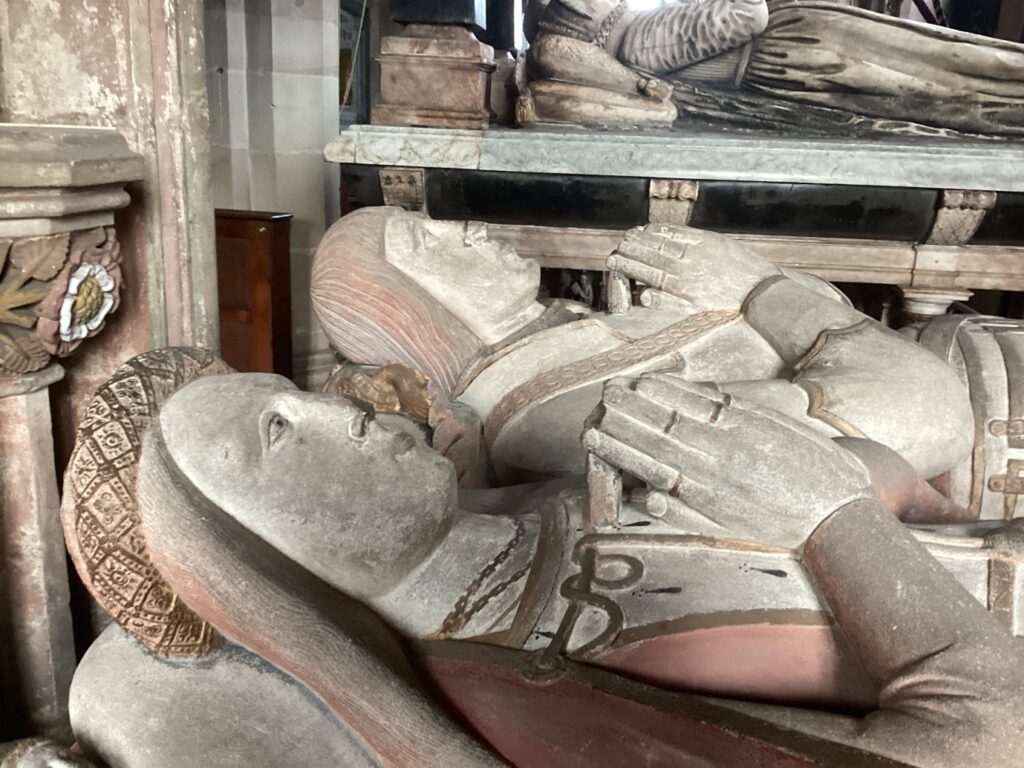 A close up photograph of the faces of the effigies of Sir Henry Vernon and Anne Talbot. Both effigies are lying down next to each other, dressed in finery, with their hands together in prayer. 