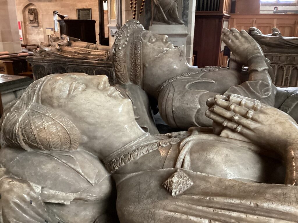 A close up photograph of the faces of the effigies of Sir Richard Vernon and Benedicta Ludlow. Both effigies are lying down next to each other, dressed in finery, with their hands together in prayer. 
